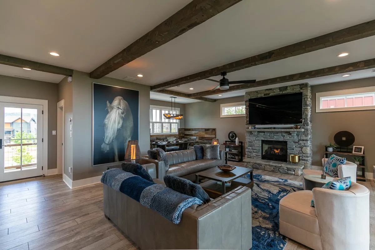 A warmly lit living space with a grand stone fireplace, open floor plan, and a large portrait of a horse as a focal point. Comfortable seating invites relaxation, and the serene decor fosters a sense of calm and luxury, ideal for leisurely evenings or focused work by the fire.
