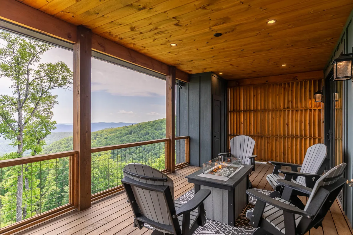 A cozy outdoor fire pit with Adirondack chairs arranged in a circle faces a panoramic mountain view. The setting is inviting, ideal for evening socializing, stargazing, or unwinding after a day of activity.