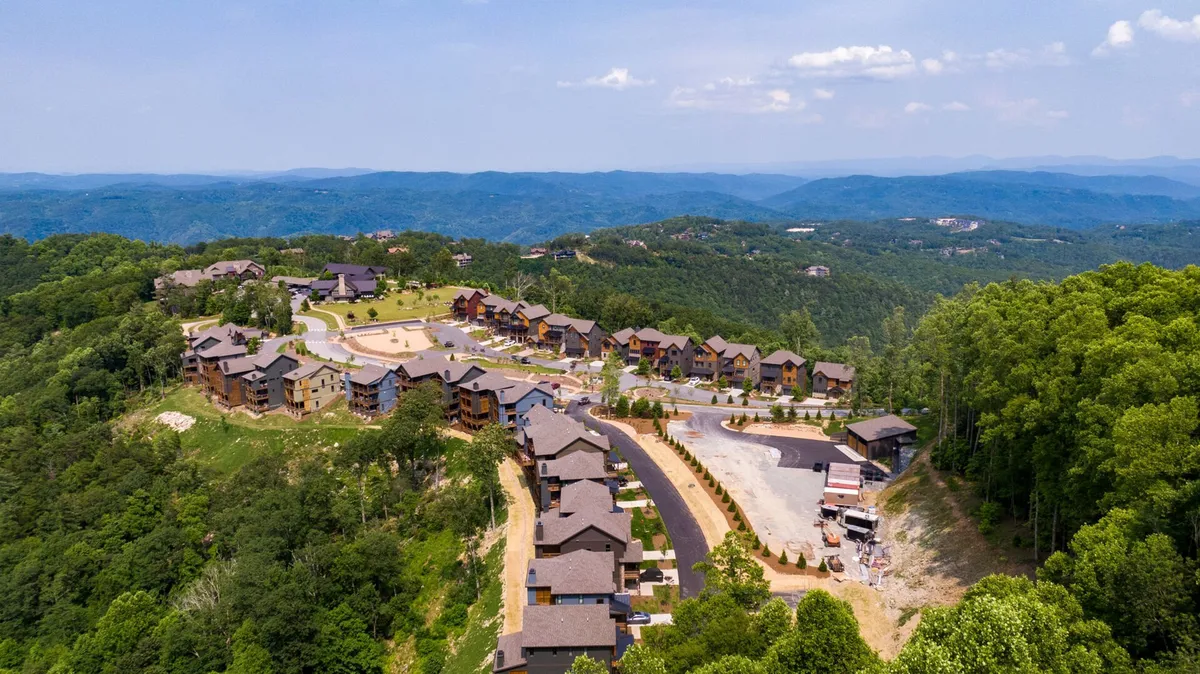 A sweeping view of the Blue Ridge Mountain Club community, with winding roads weaving through rolling, tree-covered mountains. The expansive landscape showcases the untouched wilderness and serenity of the area, inviting exploration and outdoor adventures.