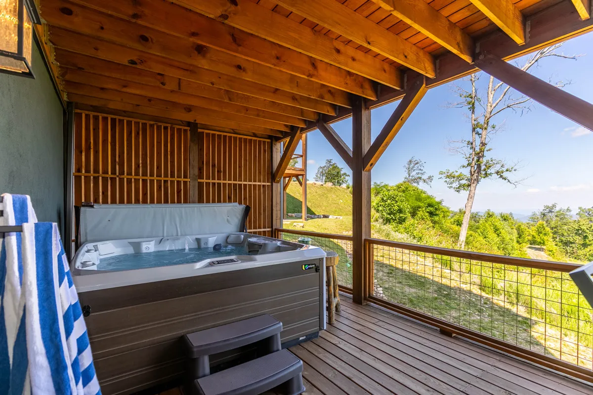 A hot tub on a wooden deck, perfectly positioned for panoramic views of the scenic mountain landscape. This tranquil setting hints at relaxation and rejuvenation just steps from the home.