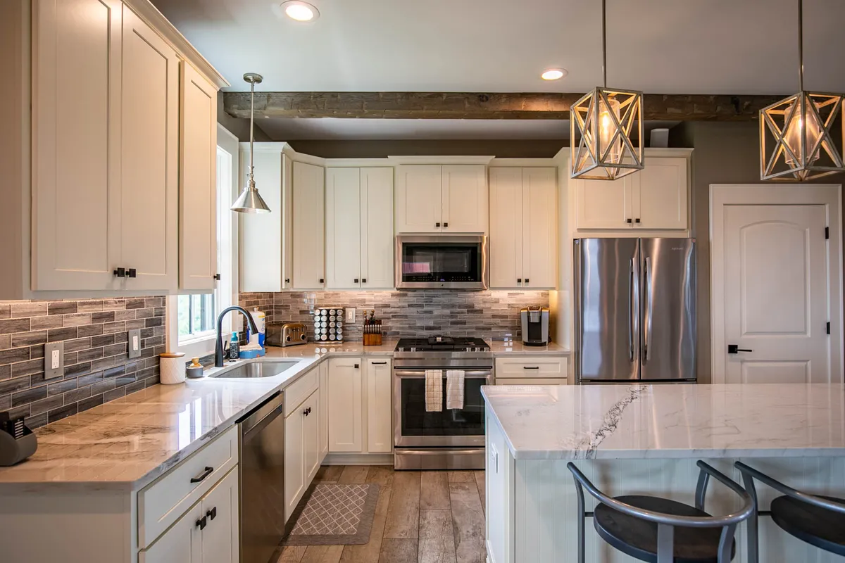 A bright, spacious kitchen featuring a large kitchen island, state-of-the-art stainless steel appliances, eye-catching pendant lights, and beautifully tiled backsplash. The setup suggests a space perfect for cooking, entertaining, and family gatherings.