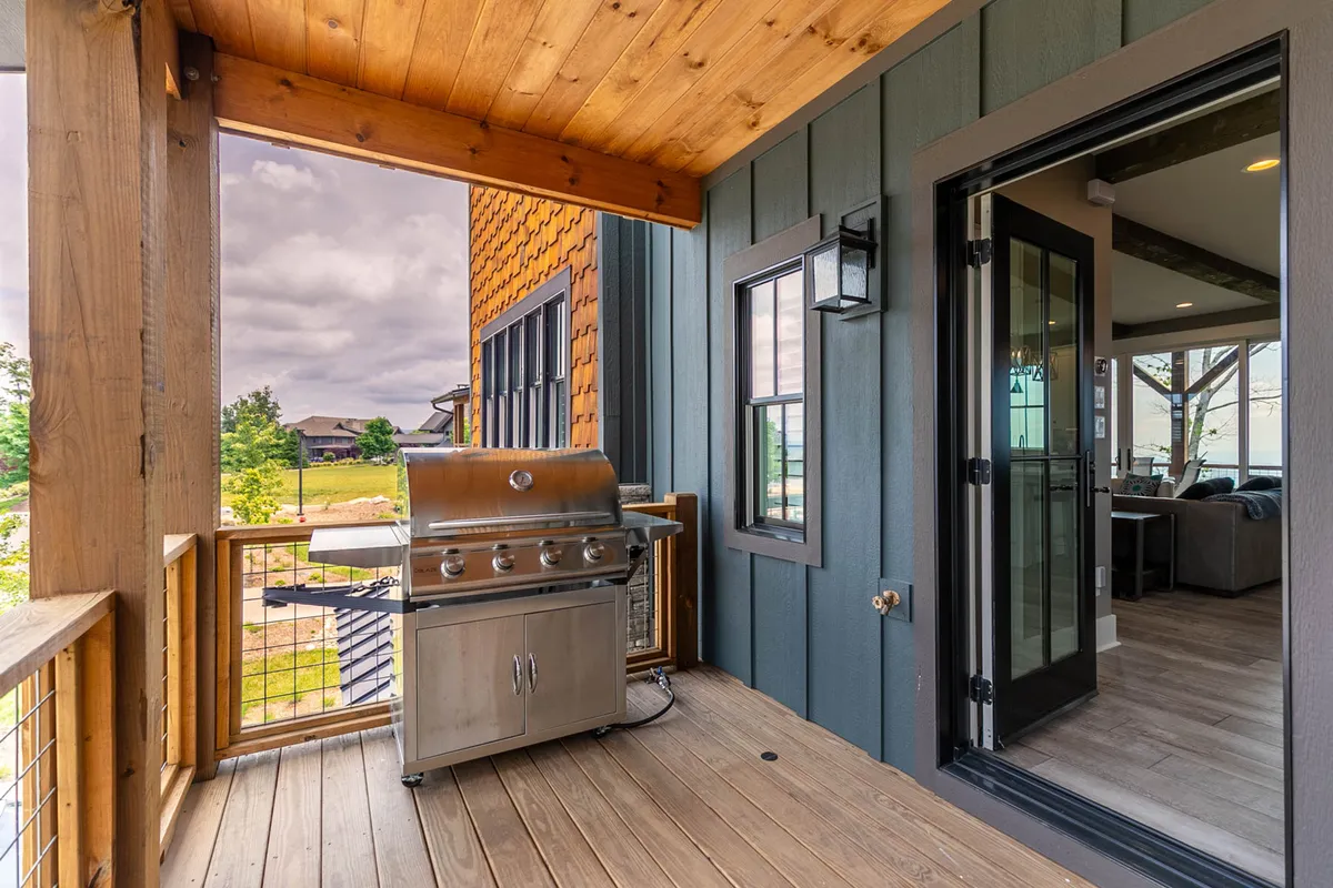An exterior patio area with a grill, outdoor seating, and a wooden ceiling, seamlessly connecting the indoors to the outdoors. The scene suggests relaxation, outdoor dining, and sociable gatherings in a private, secure environment.