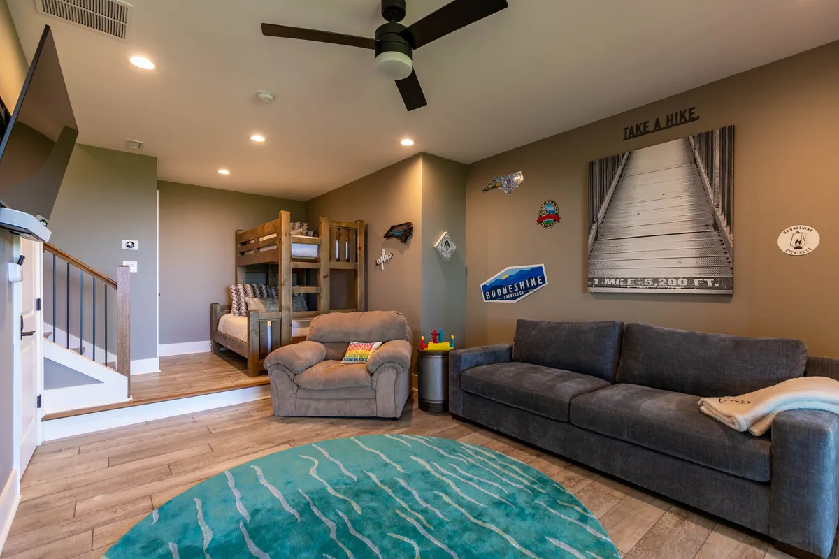 A family-friendly bedroom with bunk beds, a comfortable sofa, decorative wall art, and a cozy area rug. The room invites relaxation and play, perfectly suited for children or additional guests.
